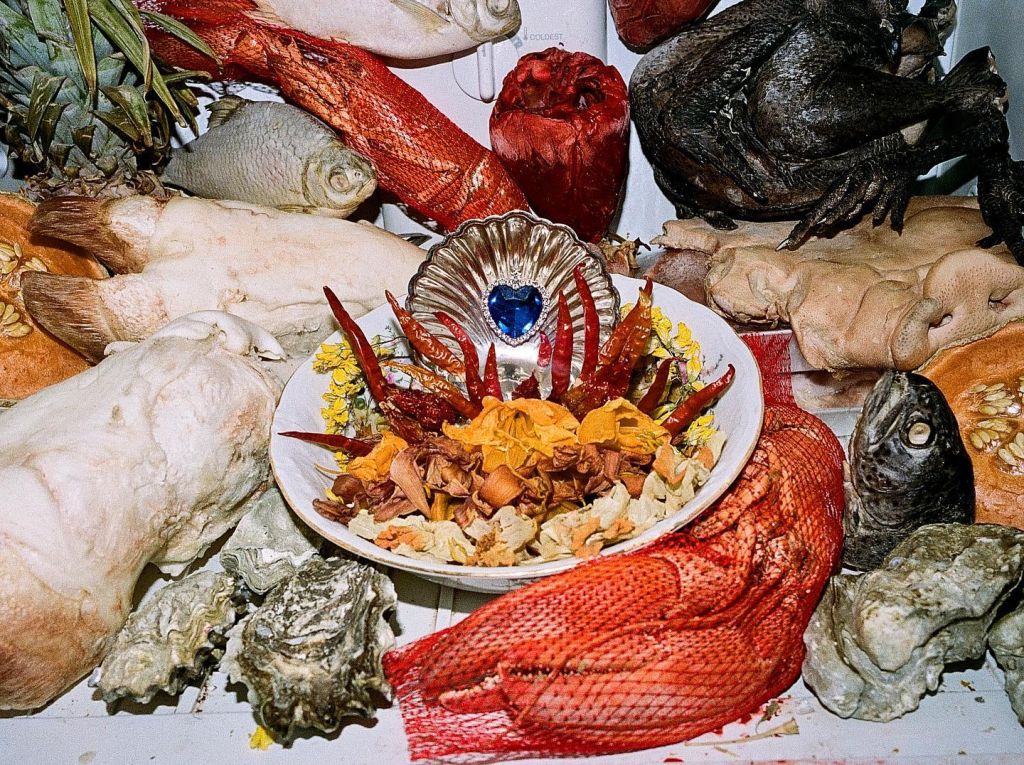 Nature morte d'un festin un peu gore, mêlant pieds de porc, fruits de mer et bijoux