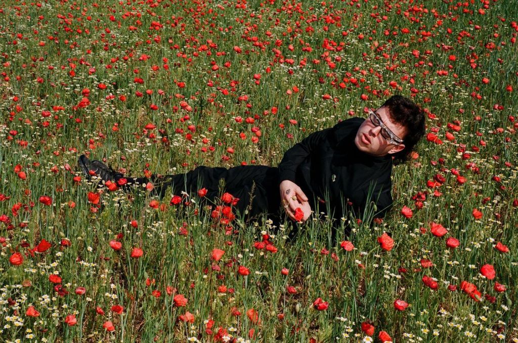 Un homme vêtu de noir allongé dans un champ de coquelicots