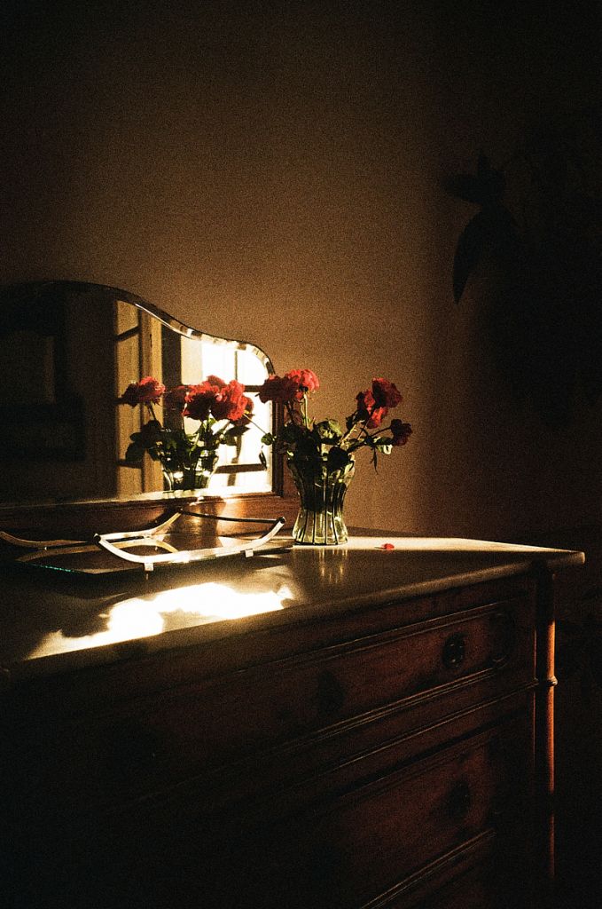 Photographie de Sarah Carrier montrant une commode avec un bouquet de roses et un miroir