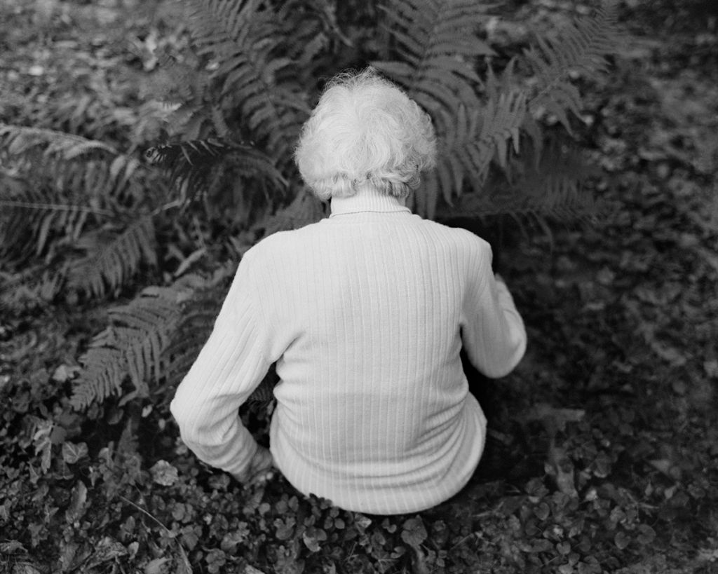 Photographie de Balázs Turós montrant une femme âgée de dos, assise dans la forêt