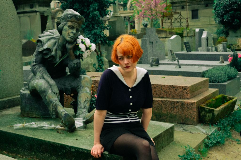 Femme assise sur une tombe, dans un cimetière