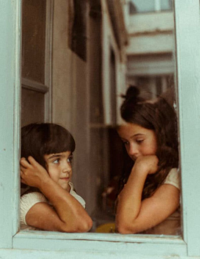 Deux enfants se regardant devant une fenêtre