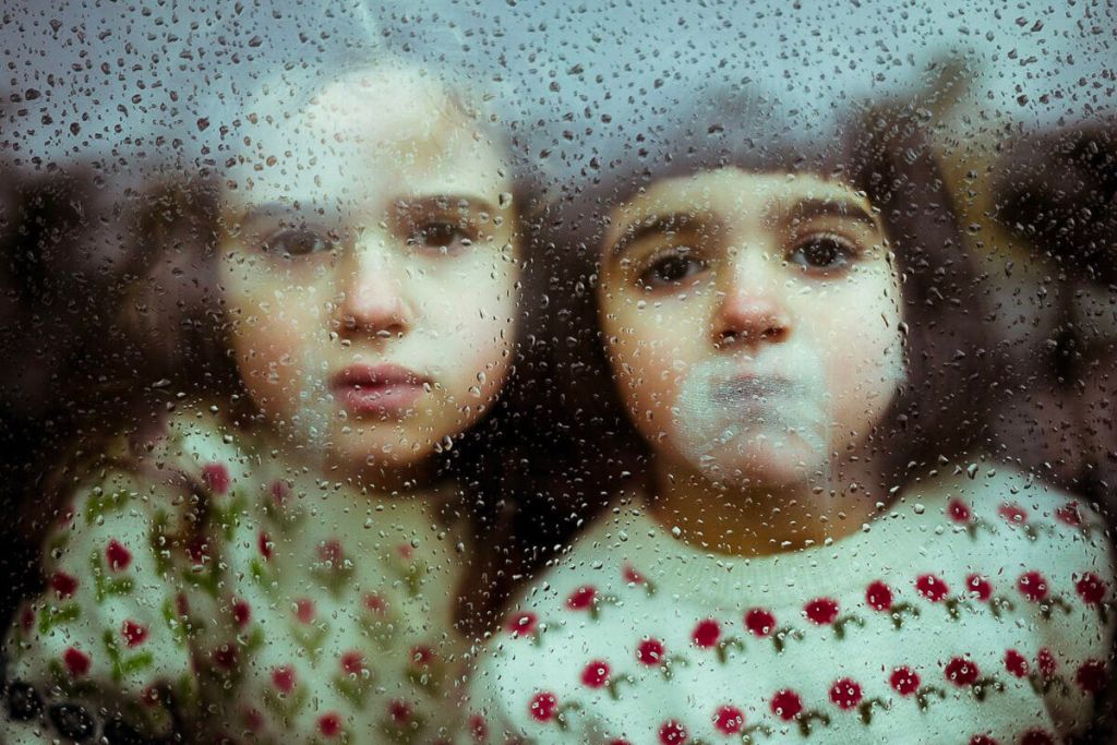 Deux enfants derrière une fenêtre