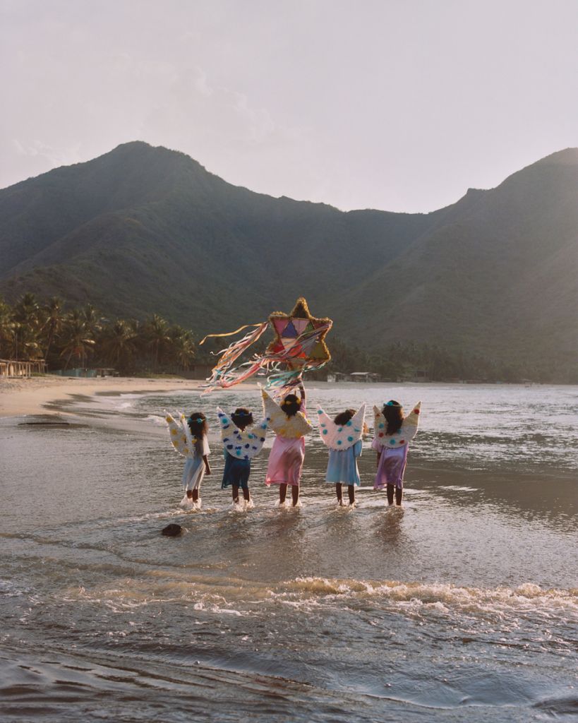 Groupe d'enfants les pieds dans l'eau portant des ailes d'ange