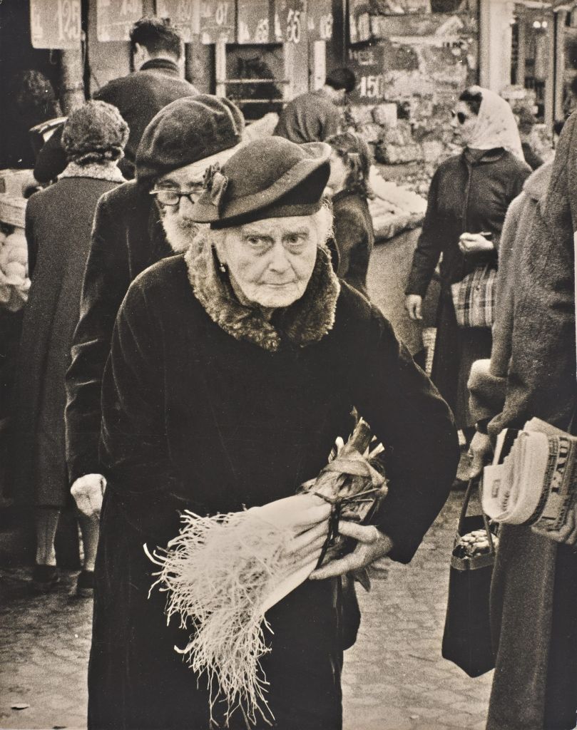 Photo ancienne d'une dame âgée rue Mouffetard. Elle porte un chapeau et un manteau avec un col en fourrure. 