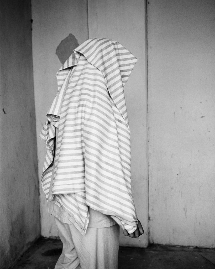 photo en noir et blanc, une personne de dos porte un tissu qui lui recouvre la tête et le dos