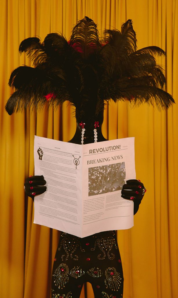 Une personne avec une coiffe en plume lit le journal