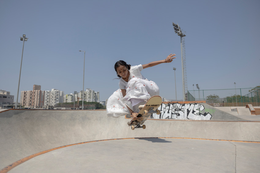 Une jeune fille faisant une figure de skateboard dans un skatepark