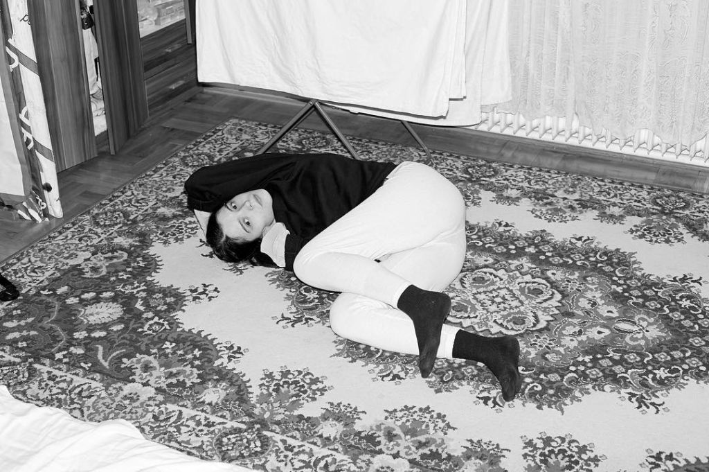 Une jeune femme est allongée par terre sur un tapis 