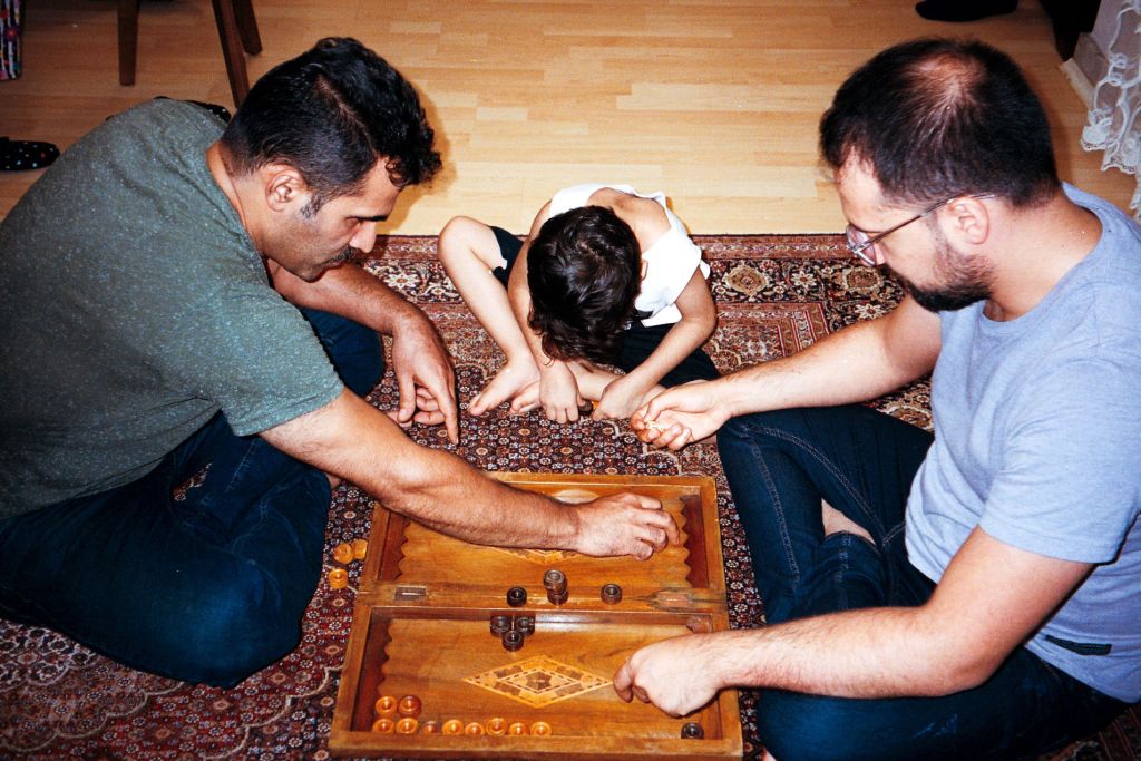 Deux hommes et un petit garçon jouent par terre à un jeu en bois