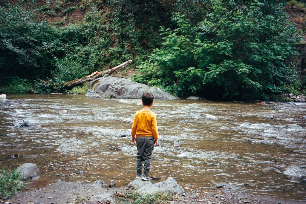 Petit garçon sur un rocher face à la rivière