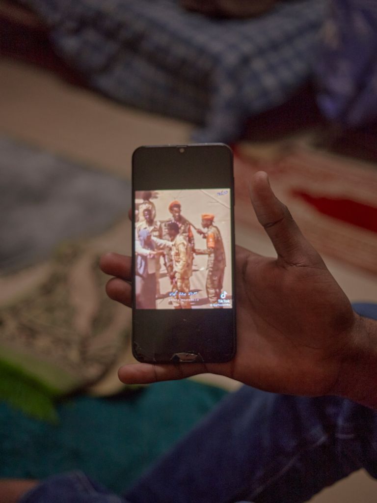 Maintenant un smartphone affichant une vidéo TikTok avec des hommes en uniforme militaire