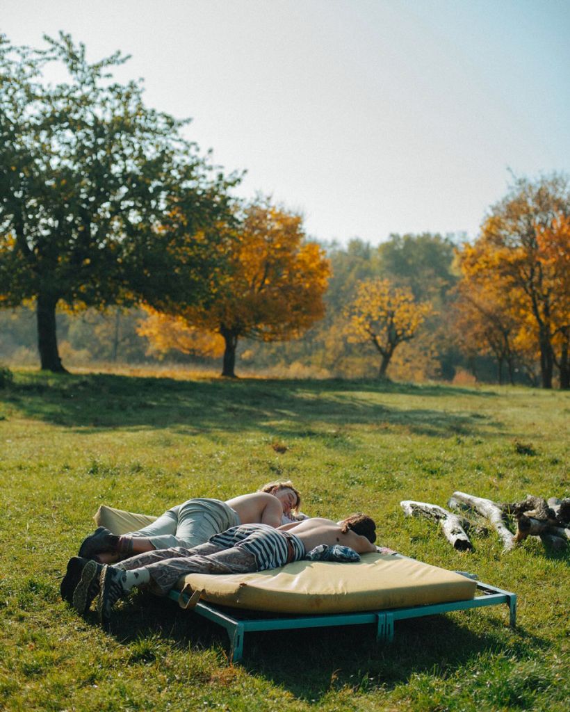 Deux jeunes personnes. torses nus, sont allongées sur un matelas à la campagne au soleil. 