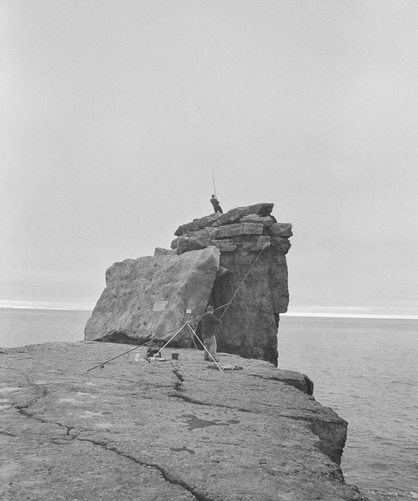 Des pêcheurs pêchent sur un promontoir rocheux à la mer. 