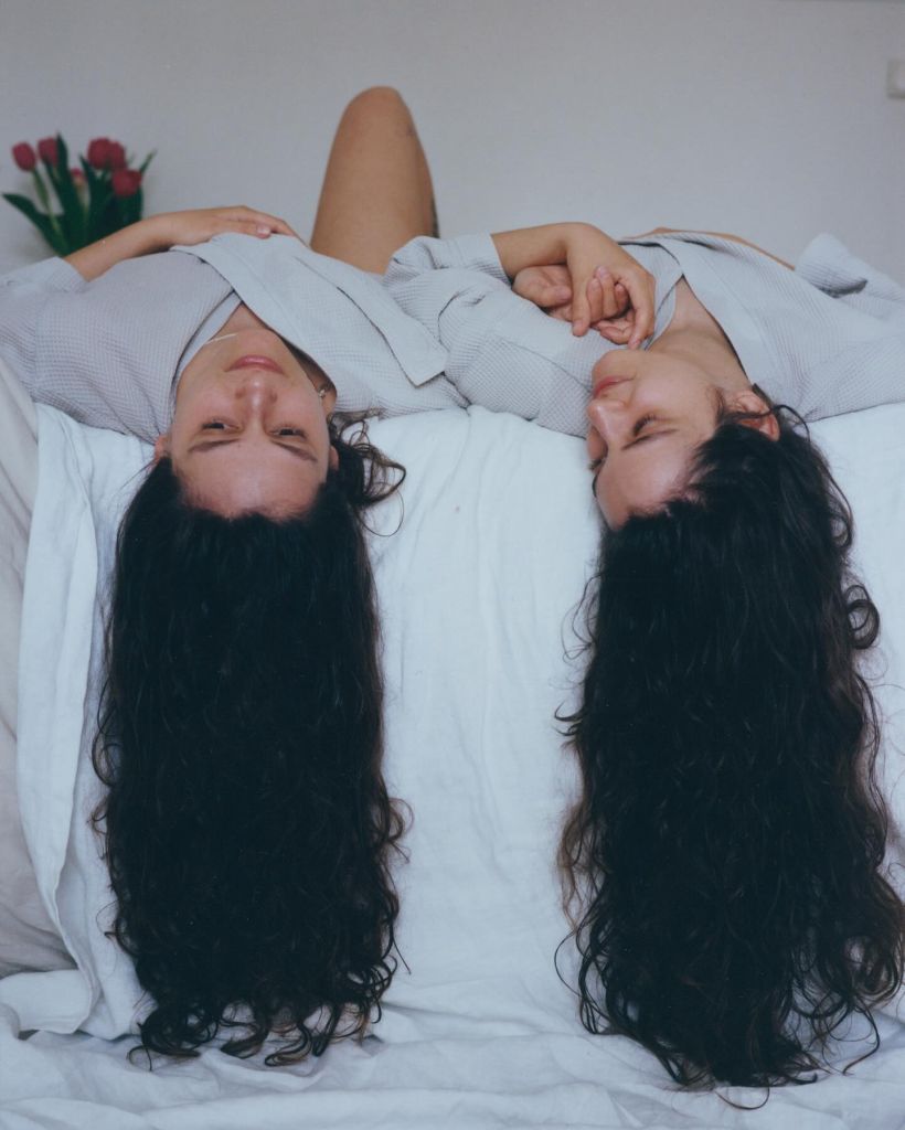 Deux femmes allongées sur un lit la tête en bas
