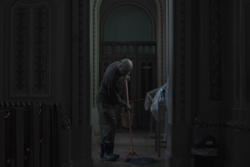 Un homme passe le balais dans une chapelle.