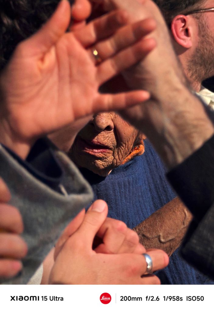 Un visage se distingue entre des mains