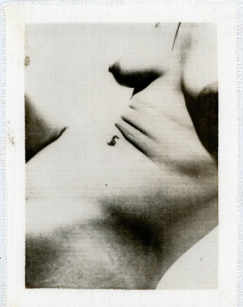 Un fragment de corps, torse, poitrine et début de bassin, en noir et blanc présenté de façon oblique.