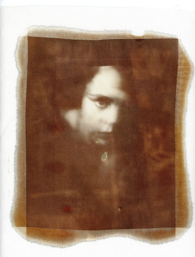 Un visage transparaît d'une toile de fond brune, le regard fixant l'objectif.