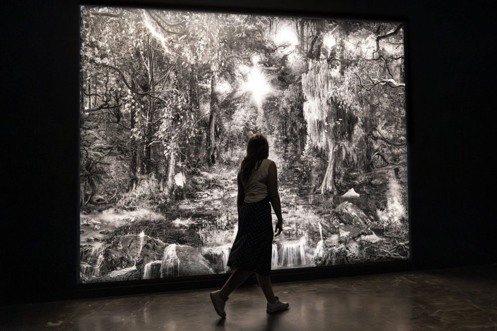 Spectatrice se baladant face à une peinture numérique de Nicolas Baier.