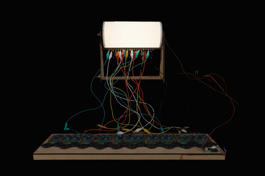 Un clavier en bois relié à un écran blanc par de nombreux câbles de diverses couleurs.