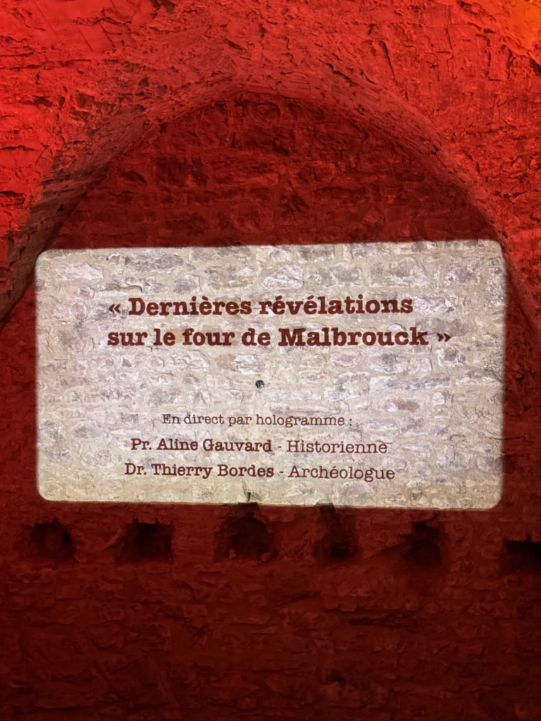 Dispositif holographique dans une cave aux teintes rouges.