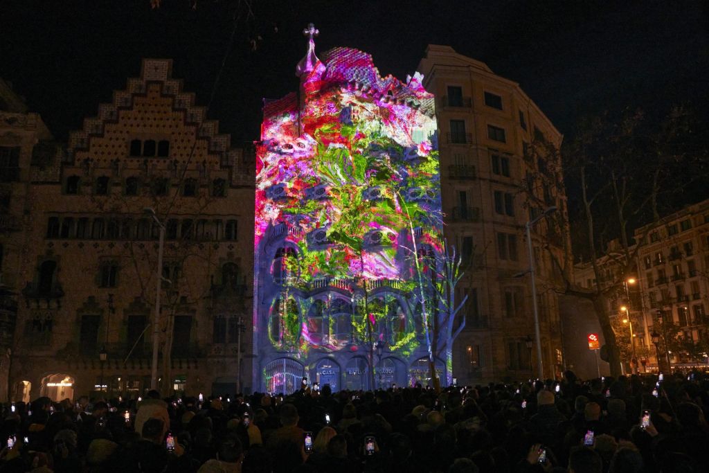 Vue nocturne de la Casa Batlló où un mapping représentant un arbre en fleurs est projeté sur la façade.