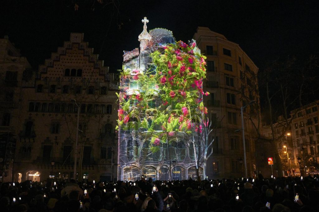 Vue nocturne de la Casa Batlló où un mapping représentant un arbre en fleurs est projeté sur la façade.