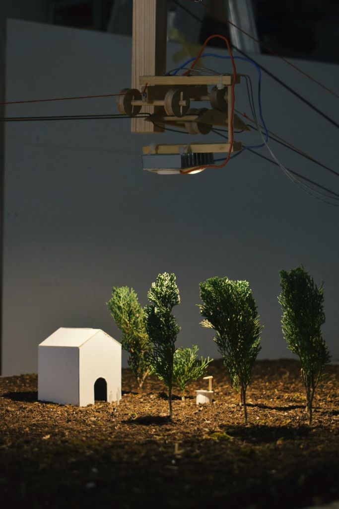 Version miniaturisée d'une maison blanche entourée par deux arbres et éclairée par des lumières artificielles.