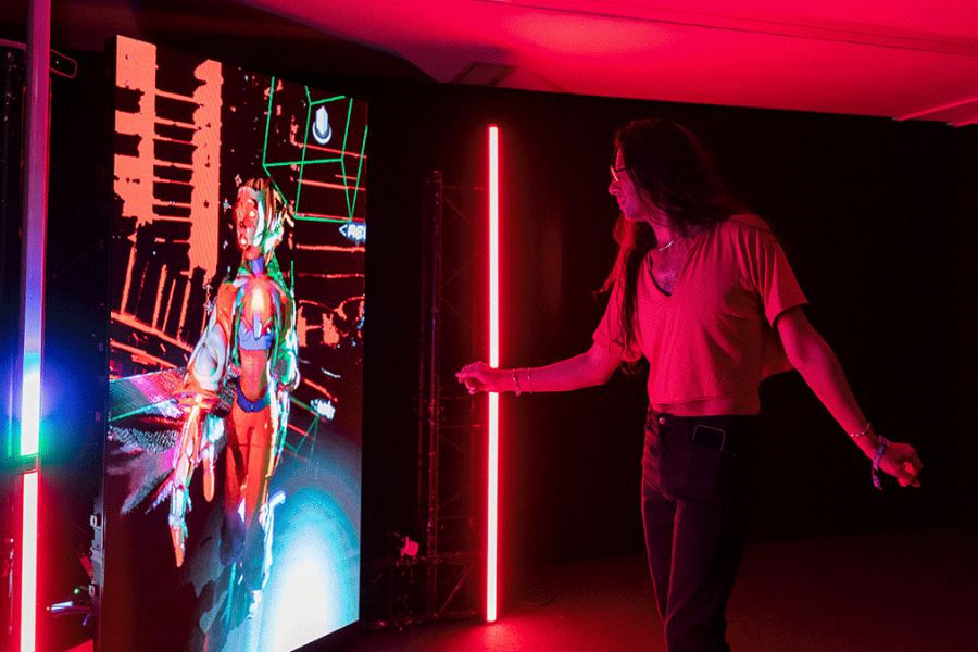 Un jeune homme aux cheveux longs interagit avec un écran interactif. 